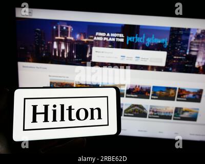 Personne détenant un smartphone avec le logo de la société américaine Hilton Worldwide Holdings Inc. Sur l'écran devant le site Web. Concentrez-vous sur l'affichage du téléphone. Banque D'Images