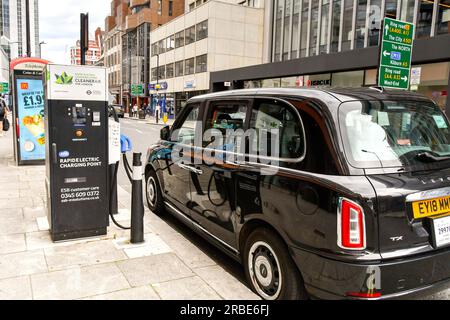 Londres, Angleterre, Royaume-Uni - 27 juin 2023 : taxi électrique branché à un point de recharge rapide dans une rue du centre de Londres Banque D'Images