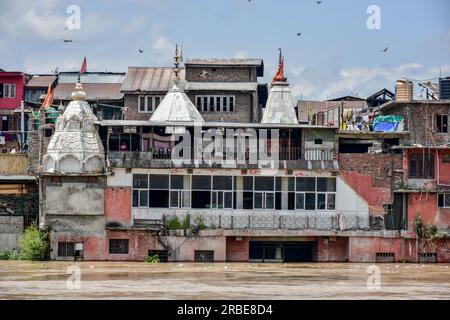 Srinagar, Inde. 09 juillet 2023. Des gens sont vus au sommet du temple alors que la rivière Jehlum est vue couler au-dessus de la marque d'alerte aux inondations suite à des pluies incessantes à Srinagar. Le Jhelum coulait au-dessus de la marque d'alerte aux inondations dans le sud du Cachemire et Srinagar en raison d'un temps nuageux et de la possibilité de nouvelles pluies au cours des prochaines 24 heures. Crédit : SOPA Images Limited/Alamy Live News Banque D'Images