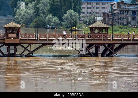 Srinagar, Inde. 09 juillet 2023. Les navetteurs marchent le long du pont de pied en bois alors que la rivière Jehlum est vue couler au-dessus de la marque d'alerte aux inondations suite aux pluies incessantes à Srinagar. Le Jhelum coulait au-dessus de la marque d'alerte aux inondations dans le sud du Cachemire et Srinagar en raison d'un temps nuageux et de la possibilité de nouvelles pluies au cours des prochaines 24 heures. Crédit : SOPA Images Limited/Alamy Live News Banque D'Images