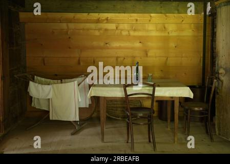 Table en bois avec chaises et bouteilles dans la petite salle de maison en bois Banque D'Images