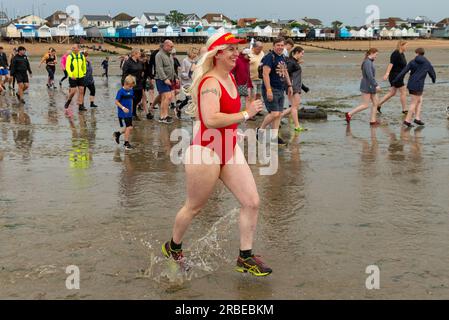 Thorpe Bay, Essex, Royaume-Uni. 9 juillet 2023. Une section du port de Mulberry du jour J de la Seconde Guerre mondiale a été échouée dans l'estuaire de la Tamise à plus d'un mile au large de la côte de Thorpe Bay près de Southend on Sea à la suite de difficultés lorsqu'il a été remorqué en 1944 et s'y trouve depuis. L'immense caisson de Phoenix est accessible à pied brièvement à marée basse, bien que beaucoup aient dû être secourus par la RNLI à mesure que les eaux de mer montent. Cette course de charité amusante d'environ 1800 participants au port et retour a été soigneusement chronométrée et surveillée pour assurer la sécurité des coureurs, les recettes allant à la RNLI. Costume Baywatch Banque D'Images