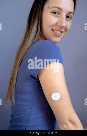 Fille assise avec un patch de glucose de capteur sur son bras Banque D'Images