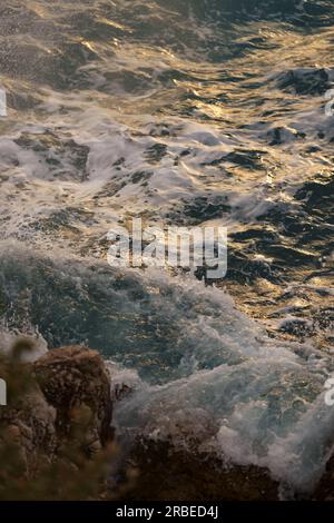 Vagues de mer s'écrasant contre les rochers de la rive méditerranéenne pendant le coucher du soleil, contenu de voyage Banque D'Images