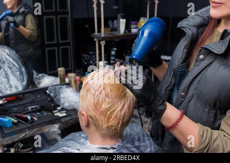 main de une coiffeur dans noir gants appliquant colorant à le femelle  cheveux dans une beauté salon. 22677369 Photo de stock chez Vecteezy