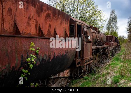 Locomotive rouillée en acier avec wagon à charbon abandonnée au cimetière de train sur la vieille voie ferrée. Banque D'Images