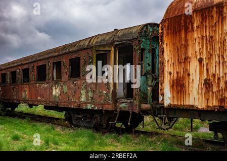 Vieux wagon rouillé de voyageurs abandonné sur le champ de ciment de train Banque D'Images