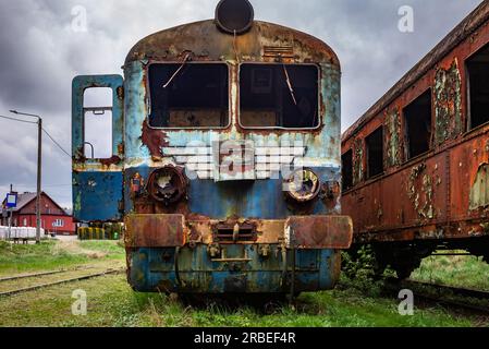 Vieux train électrique rouillé à unités multiples mis hors service et abandonné sur voie ferrée sur un terrain herbeux vert Banque D'Images