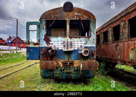 Vieux train électrique rouillé à unités multiples mis hors service et abandonné sur voie ferrée sur un terrain herbeux vert Banque D'Images