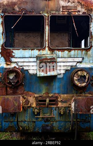 Vieux train électrique rouillé à unités multiples mis hors service et abandonné sur voie ferrée sur un terrain herbeux vert Banque D'Images