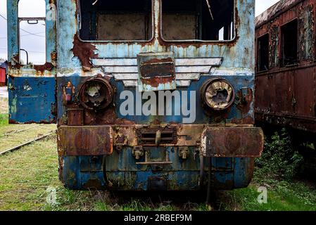 Vieux train électrique rouillé à unités multiples mis hors service et abandonné sur voie ferrée sur un terrain herbeux vert Banque D'Images