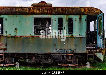 Vieux train électrique rouillé à unités multiples mis hors service et abandonné sur voie ferrée sur un terrain herbeux vert Banque D'Images