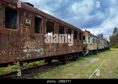 Vieux wagon rouillé de voyageurs avec des unités multiples électriques abandonnées sur le champ cimétaire de train Banque D'Images