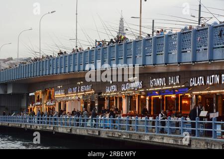 Une ligne de restaurants turcs et de pêcheurs pêchant le long du pont de Galata sur la Corne d'Or et le détroit du Bosphore, Istanbul, Turquie / Turkiye. Banque D'Images