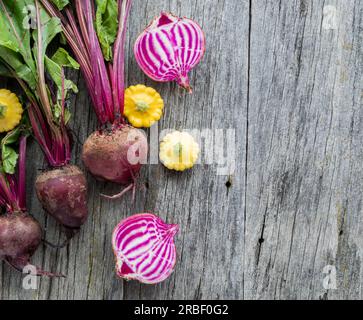 Betteraves bio crues fraîches avec patty pan courge sur une planche rustique. Banque D'Images