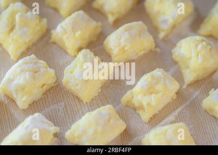 Dessert au caillé sucré. Des morceaux de pâte tranchés reposent sur la table dans la farine. Vue d'en haut. Recette pour un délicieux dessert à la maison. Banque D'Images