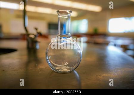 flacon sur une table en résine noire avec un fond de salle de sciences de lycée. Banque D'Images