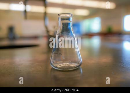 flacon sur une table en résine noire avec un fond de salle de sciences de lycée. Banque D'Images