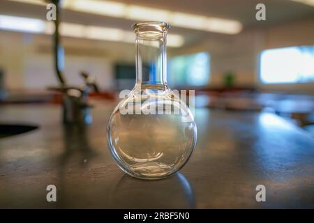 flacon sur une table en résine noire avec un fond de salle de sciences de lycée. Banque D'Images