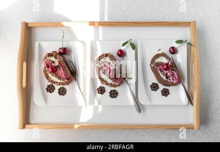 Tranches de gâteau au chocolat avec des cerises sur des assiettes blanches Banque D'Images