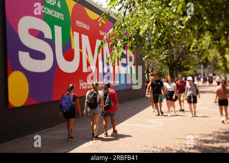 Les gens marchent le long du trottoir devant le port de Toronto Banque D'Images
