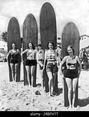 Californie du Sud : c. 1930. Six jeunes femmes sont prêtes avec leurs planches de surf sur une plage du sud de la Californie. Banque D'Images