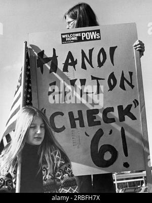 Fairfield, Californie : 16 février 1973 Une femme à la base aérienne de Travis tenant un panneau 'Hanoi Hilton, Check 6' alors qu'un avion arrive transportant des prisonniers de guerre du Vietnam. Banque D'Images