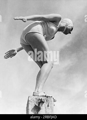 États-Unis : c. 1933 Une jeune femme debout sur une jetée et prête à plonger dans l'eau. Banque D'Images