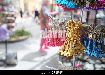 Porte-clés de souvenirs parisiens en forme de Tour Eiffel, des paquets de pièces dorées, bleues et rouges sont suspendus dans un magasin de rue Banque D'Images