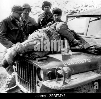 Wonju, Corée : 19 février 1951 États-Unis Les soldats de l'armée regardent un soldat communiste chinois blessé qui a été ramené du front sur le capot d'une jeep de l'armée. Banque D'Images