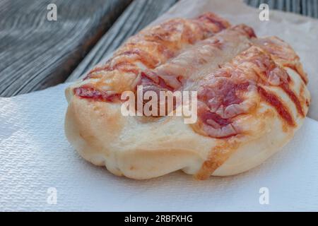 Un délicieux petit pain rempli d'une seule saucisse et de fromage fondu, garni d'une sauce tomate savoureuse. Parfait pour une collation ou un repas rapide et satisfaisant. Banque D'Images