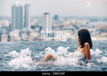 Young woman relaxing in jacuzzi sur le toit de l'hôtel et profiter de la ville. Concept de vacances d'été Banque D'Images