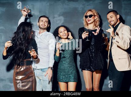 Groupe varié de jeunes dansant dans une boîte de nuit, profitez de parti et s'amuser. Jeunes amis de boire du champagne et hanging out at night club Banque D'Images