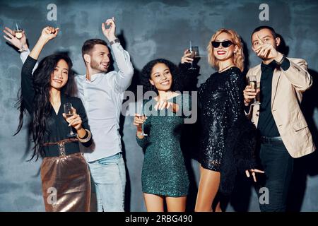 Groupe varié de jeunes dansant dans une boîte de nuit, profitez de parti et s'amuser. Jeunes amis de boire du champagne et hanging out at night club Banque D'Images