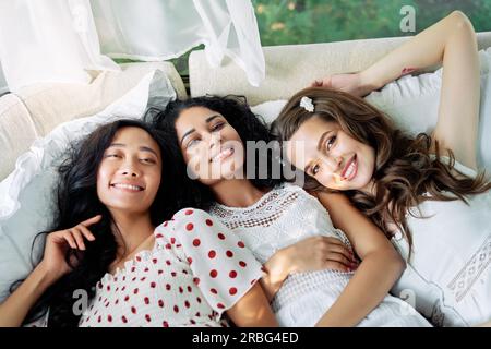 Belles filles multi ethniques s'amusent ensemble, se détendre et se coucher sur le lit à l'intérieur du camping-car. Amitié des femmes et concept de beauté des femmes. Caucasien Banque D'Images