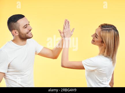 Portrait de jeune couple souriant donnant cinq à l'un à l'autre sur fond de studio. Homme et femme jouant le gâteau patty Banque D'Images