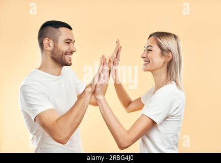 Portrait de jeune couple souriant donnant cinq à l'un à l'autre sur fond de studio. Homme et femme jouant le gâteau patty Banque D'Images