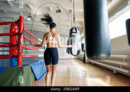 Vue arrière de la femme de fitness qui saute la corde dans la salle de gym. Entraînement cardio et fitness. Concept sportif Banque D'Images