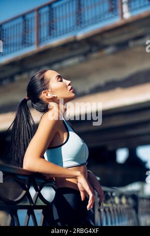 Jeune femme de la coupe se détendre et prendre une pause en courant dans la ville. Concept sportif Banque D'Images