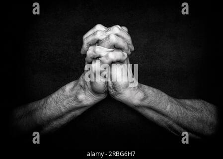 Les mains d'un homme avec les doigts croisés. C'est un geste classique d'une personne priant Dieu dans les religions chrétiennes Banque D'Images