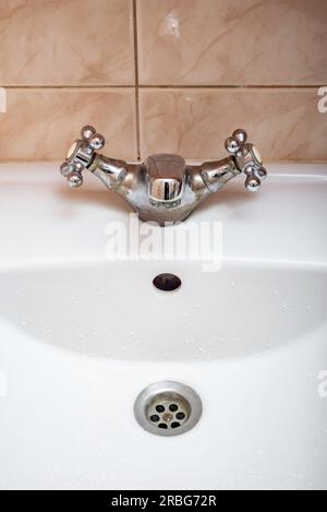 Image verticale d'un robinet fermé au-dessus d'un lavabo de salle de bain blanc Banque D'Images