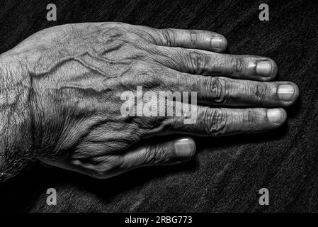 Photo en noir et blanc d'un homme main gauche sur fond sombre Banque D'Images