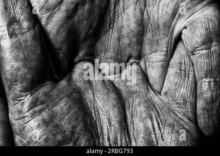 Photo noire et blanche de man les mains avec les doigts croisés sur fond sombre Banque D'Images