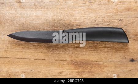 Couteau de cuisine, avec manche noir et lame en acier noir sur fond en bois naturel Banque D'Images