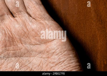 Photo de mains masculines âgées sur fond en bois. Détail de la paume de la main Banque D'Images