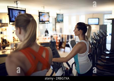 Vue latérale du middle-aged woman using machine d'exercice anaérobie in gym Banque D'Images