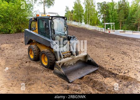mini chargeur avec godet. Une chargeuse avec un godet dégage le site pour la construction. Travaux d'amélioration foncière sur le territoire. Machine pour le déplacement du sol, sa Banque D'Images