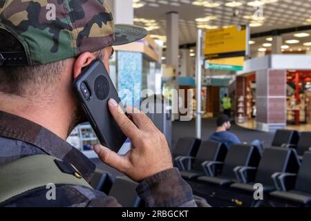 Un jeune voyageur appelle les forces de l'ordre après avoir vu quelque chose de suspect dans un aéroport international Banque D'Images