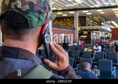 Un jeune voyageur appelle les forces de l'ordre après avoir vu quelque chose de suspect dans un aéroport international Banque D'Images