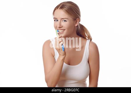 Jolie femme pratiquant l'hygiène dentaire se brossant les dents avec une brosse à dents et du dentifrice pour prévenir les caries ou caries, isolé sur blanc Banque D'Images